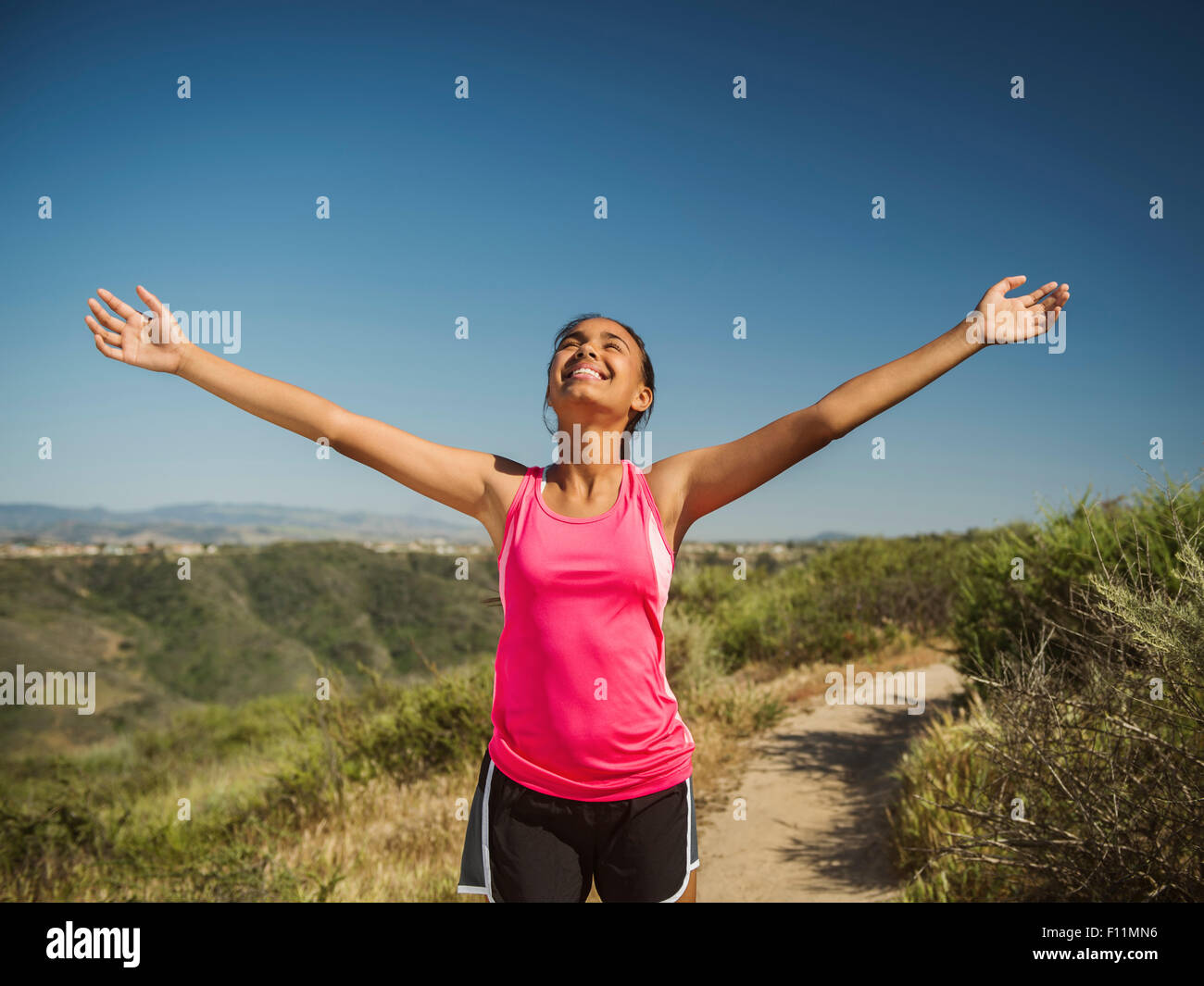 Mixed Race girl cheering on hillside path Banque D'Images