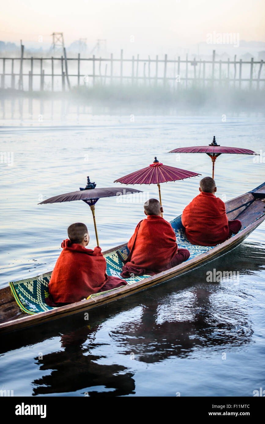 Les moines d'Asie sous les parasols en canoë sur la rivière Banque D'Images