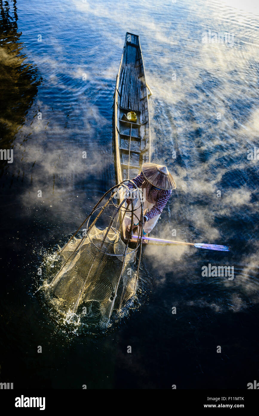 High angle view of Asian fisherman à l'aide de filet de pêche en canoë sur la rivière Banque D'Images