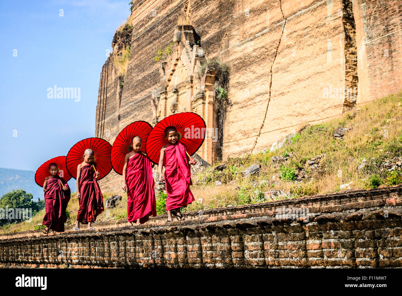 Les enfants asiatiques avec des parasols en équilibre sur mur de pierre Banque D'Images