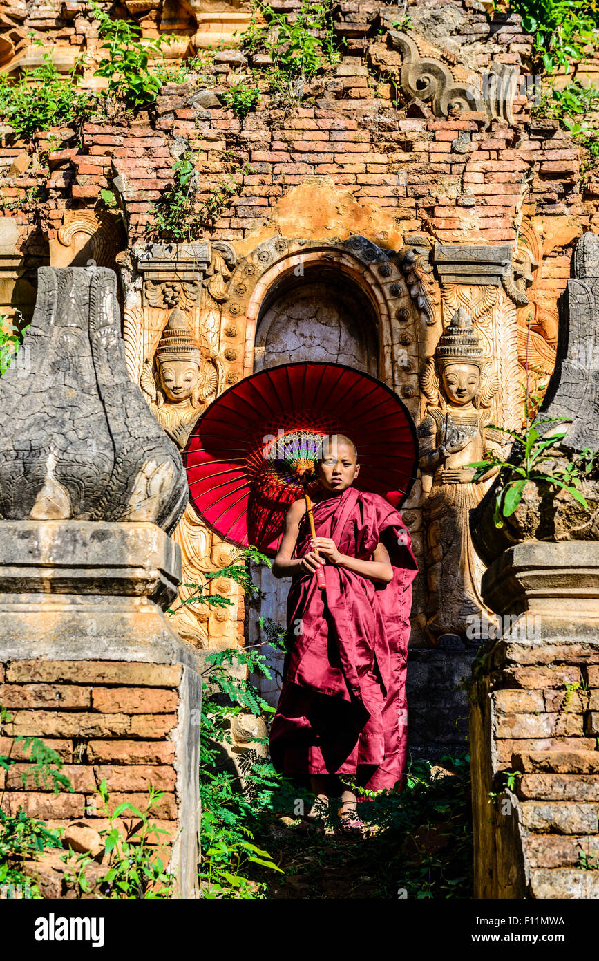 Moine asiatique en formation avec un parasol sur pied sanctuaire bouddhiste Banque D'Images
