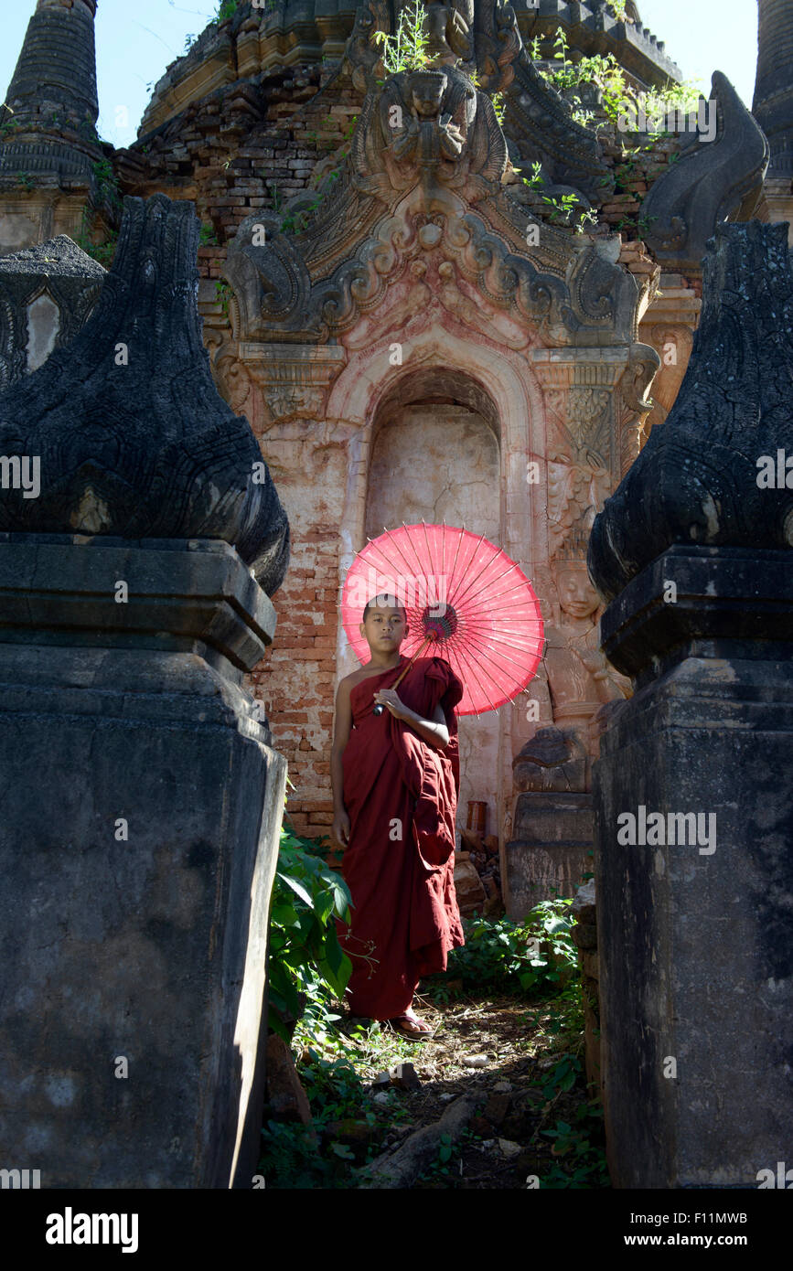 Moine asiatique en formation avec un parasol sur pied sanctuaire bouddhiste Banque D'Images