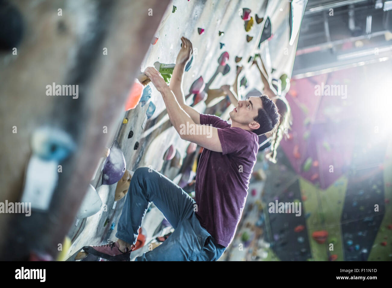 Les athlètes climbing rock wall in gym Banque D'Images