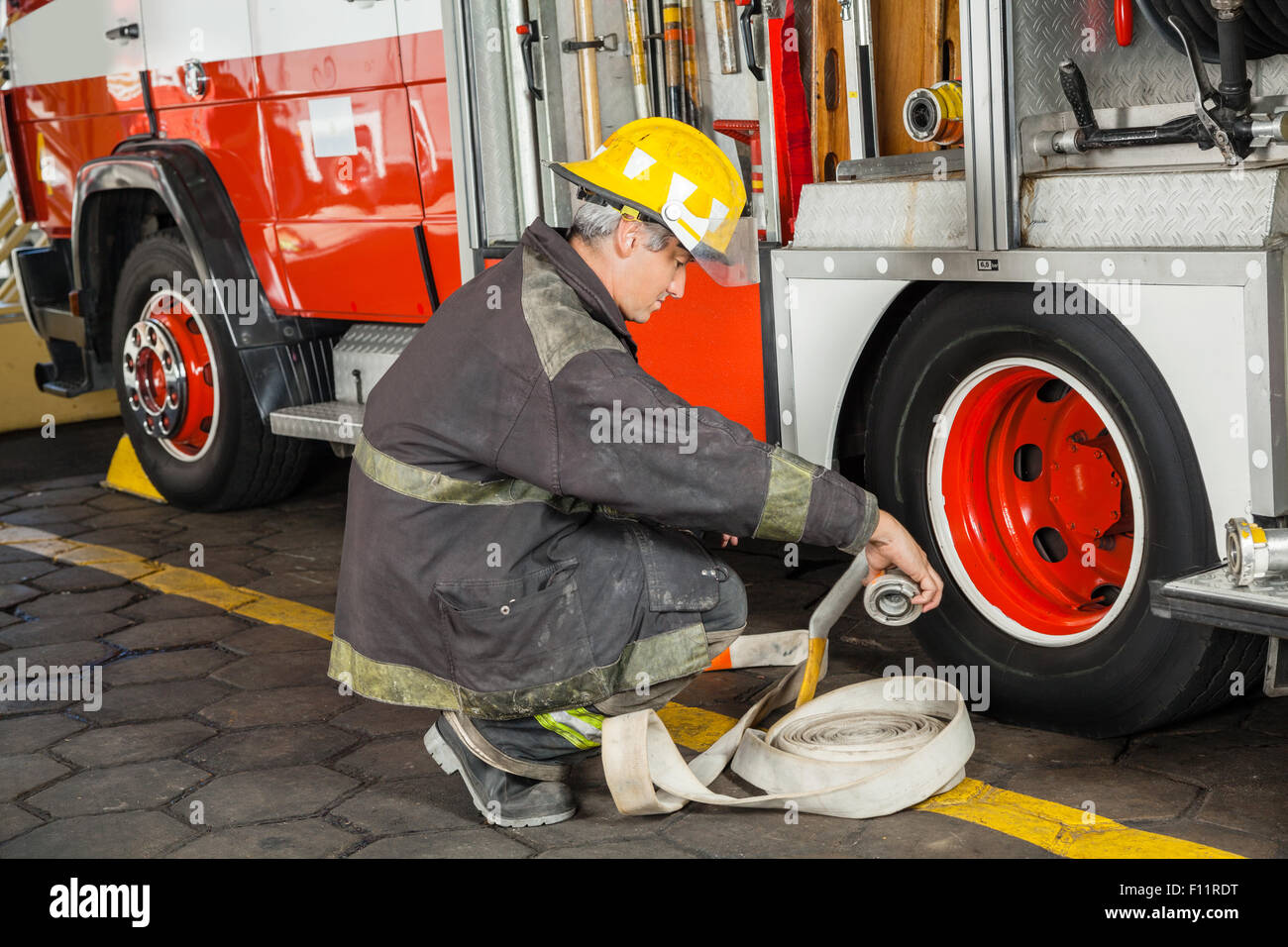 Tout en tenant accroupi pompier camion par flexible Banque D'Images