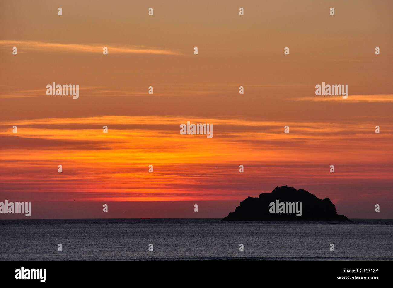 Cornouailles du nord - orange rouge et or skyscape - immédiatement après le coucher du soleil sur la mer - une île de silhouette noire Banque D'Images