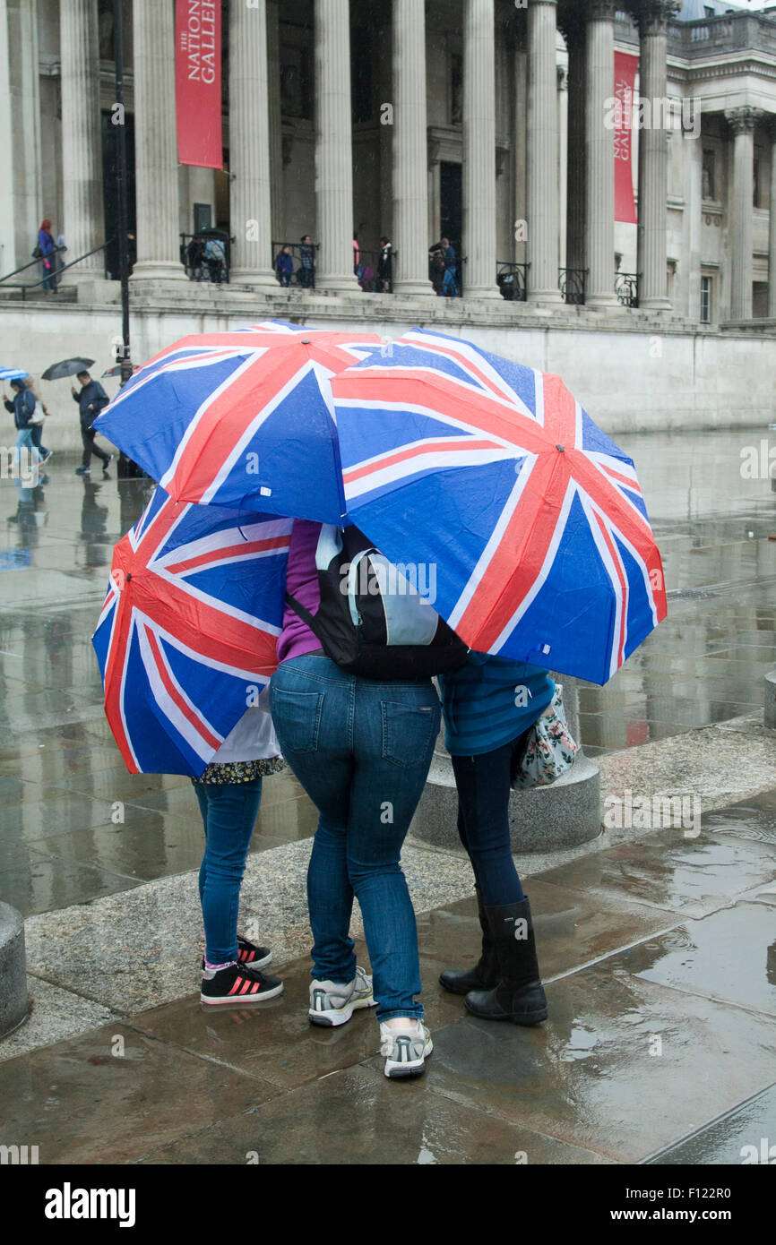 London UK. 25 août 2015. Les gens s'abritant sous les parasols à Trafalgar Square comme les pluies reviennent. Le Met Office a prévu une semaine de pluie Crédit : amer ghazzal/Alamy Live News Banque D'Images