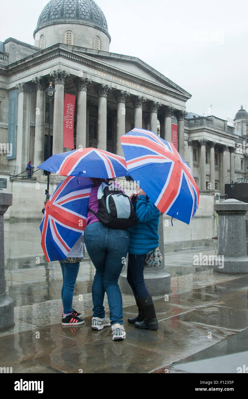 London UK. 25 août 2015. Les gens s'abritant sous les parasols à Trafalgar Square comme les pluies reviennent. Le Met Office a prévu une semaine de pluie Crédit : amer ghazzal/Alamy Live News Banque D'Images
