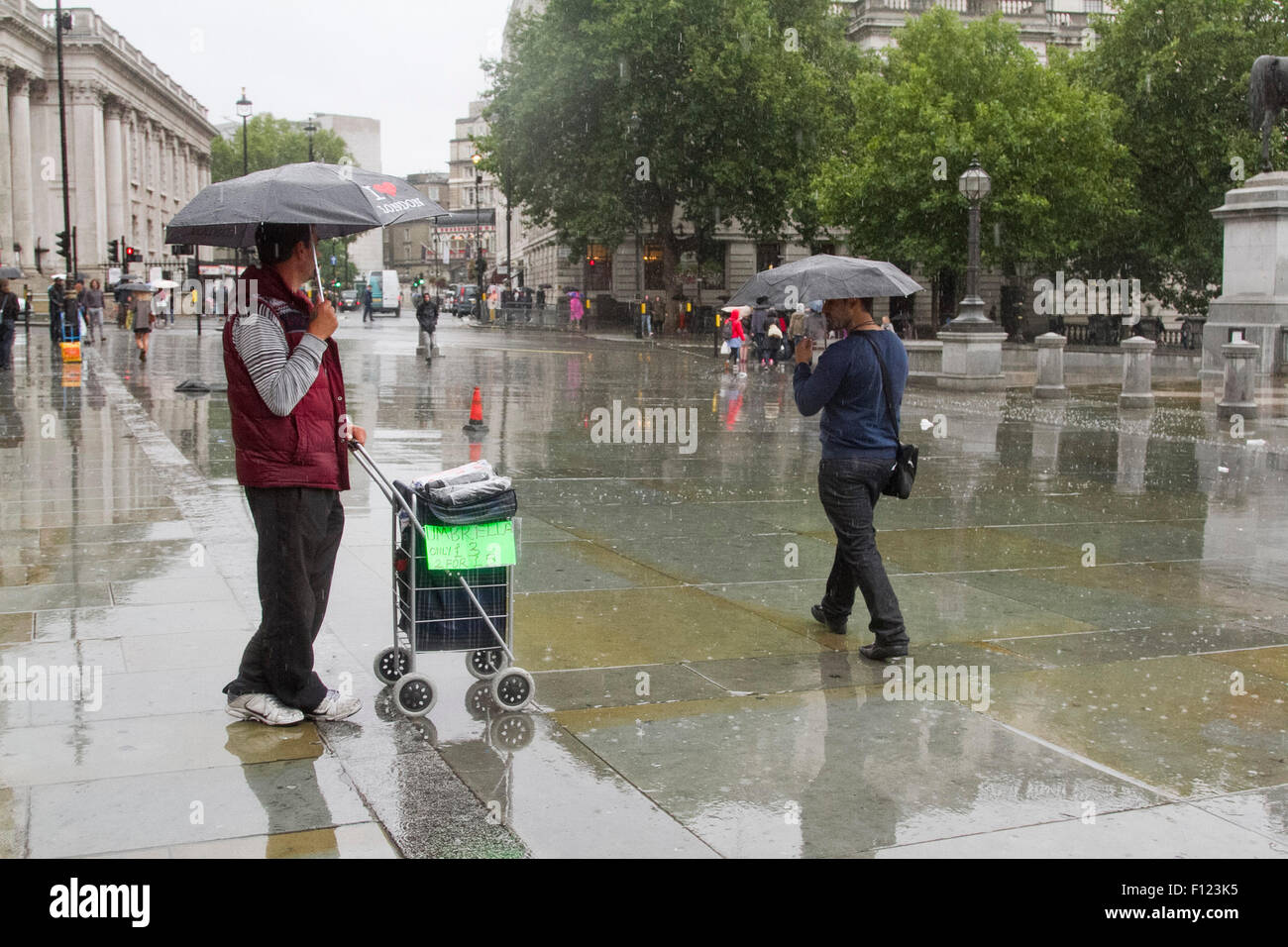 London UK. 25 août 2015. Un homme vend des parapluies à Trafalgar Square comme les pluies reviennent. Le Met Office a prévu une semaine de pluie Crédit : amer ghazzal/Alamy Live News Banque D'Images