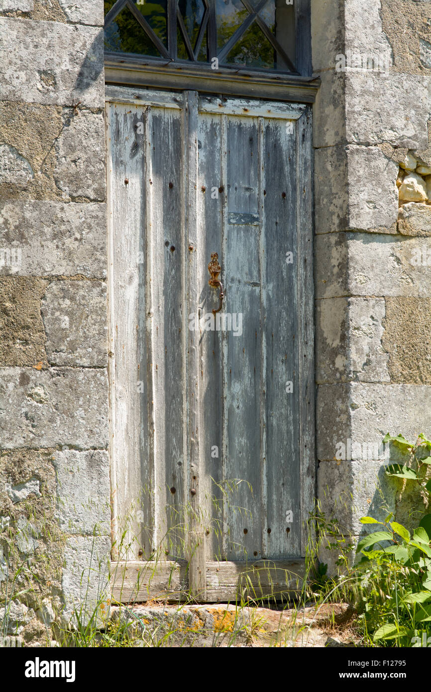 Vieille porte en bois endommagés et battues à la propriété à St Thomas de Conac, région des Charentes, France Banque D'Images