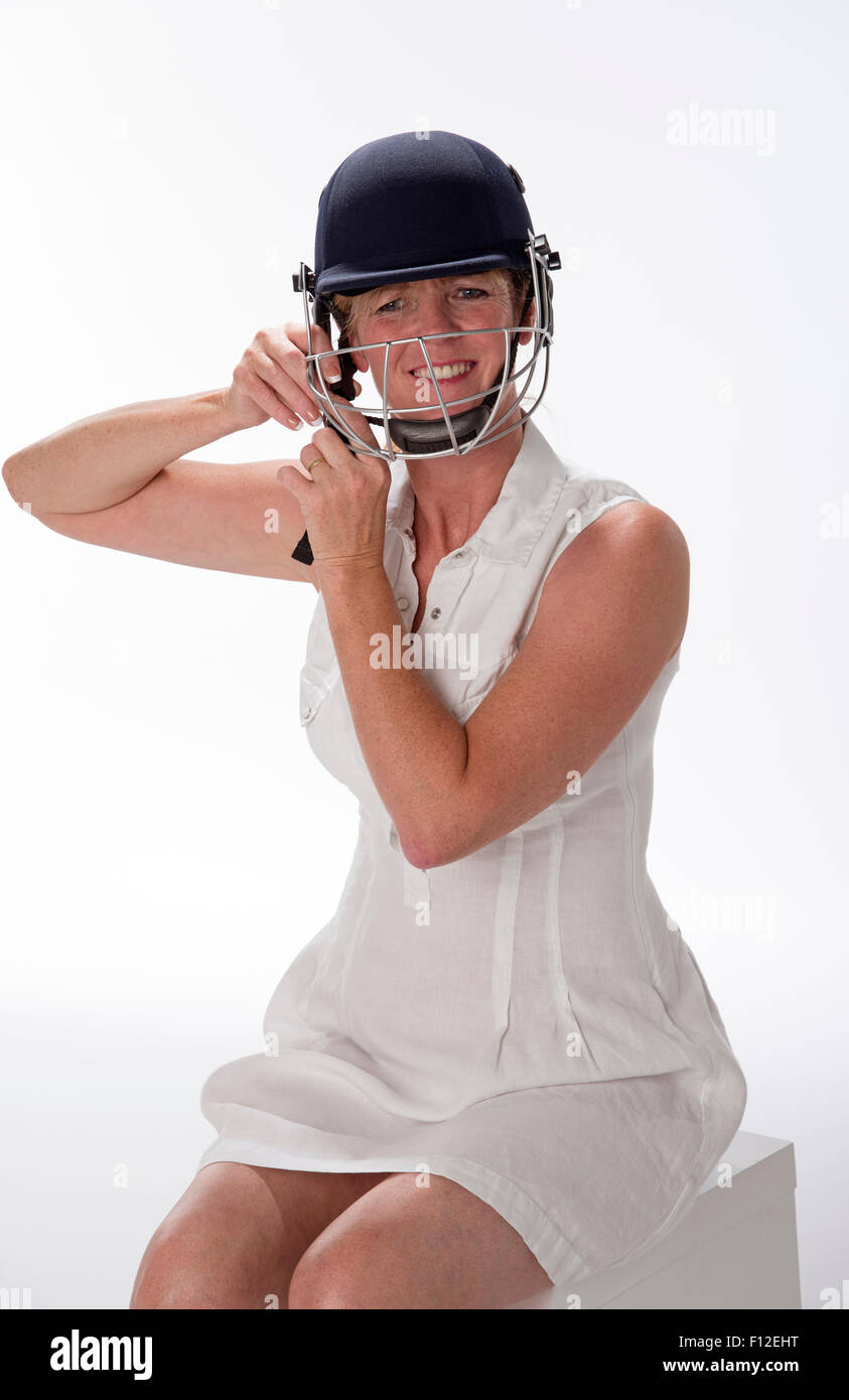 Portrait d'une femme cricketer ajustant son casque de sécurité Banque D'Images