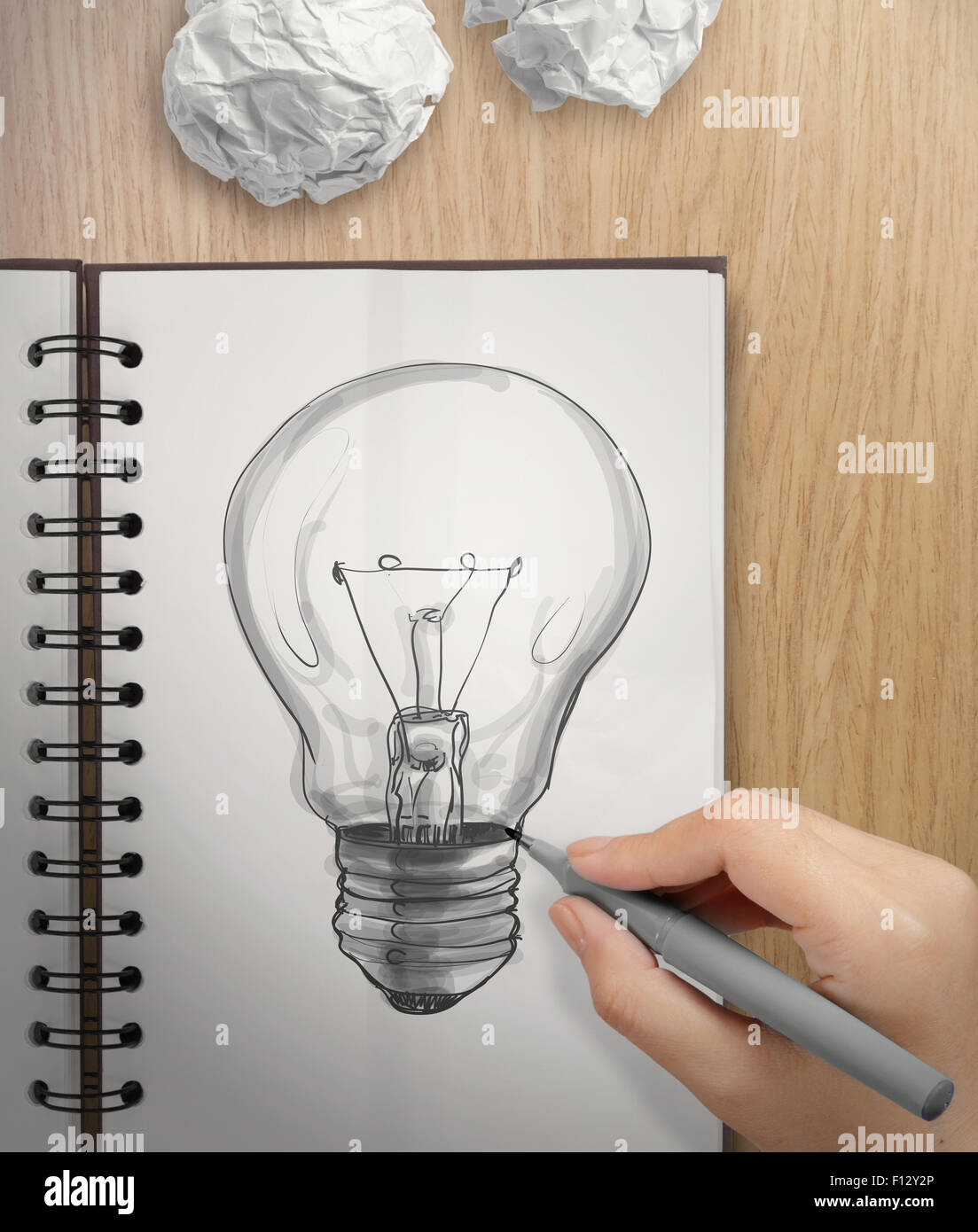 La main avec un stylo dessin Light bulb on remarque livre comme concept Banque D'Images