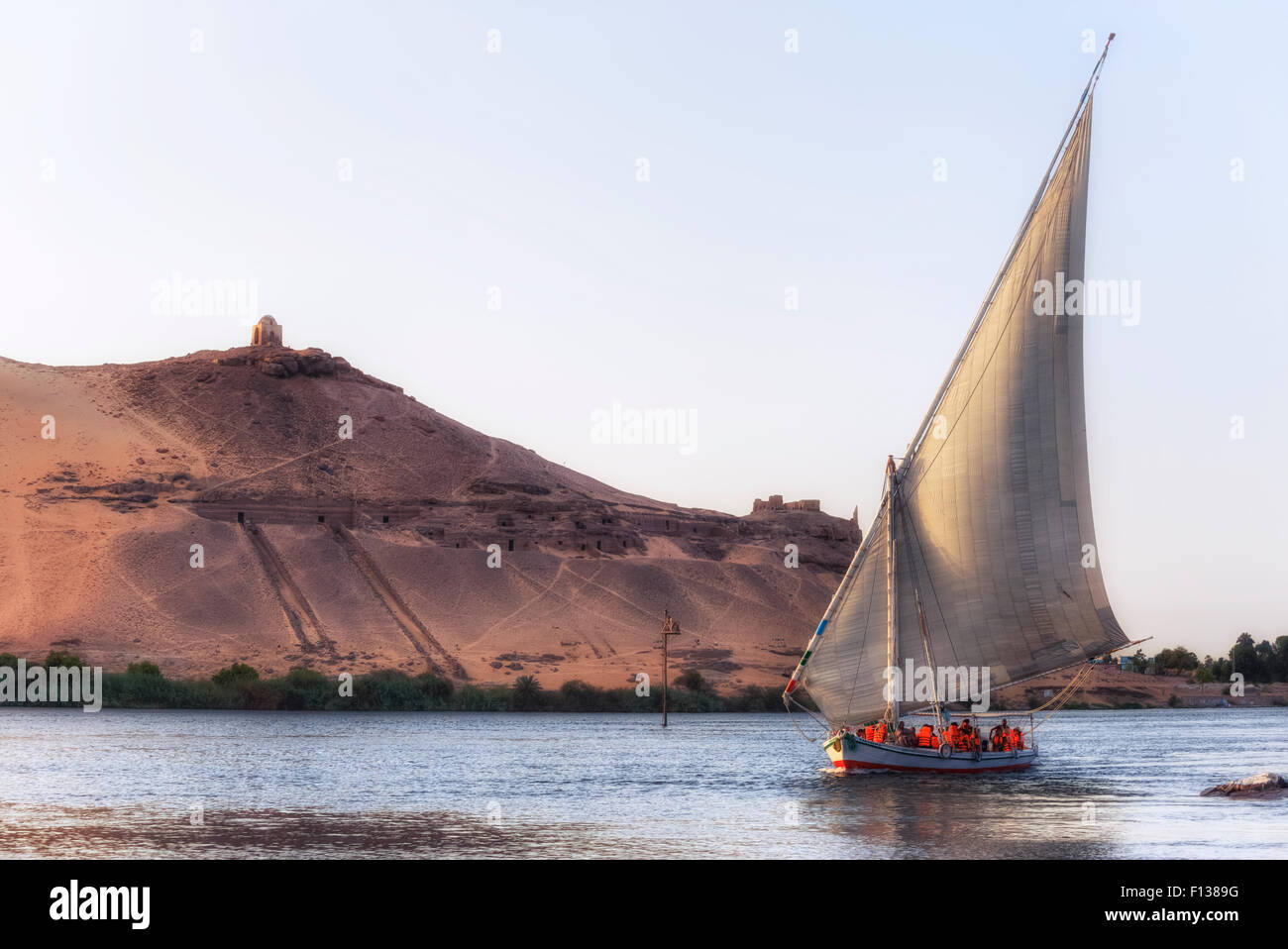 Bateau à une felouque sur le Nil au coucher du soleil sur les tombes des nobles, Assouan, Egypte, Afrique du Sud Banque D'Images