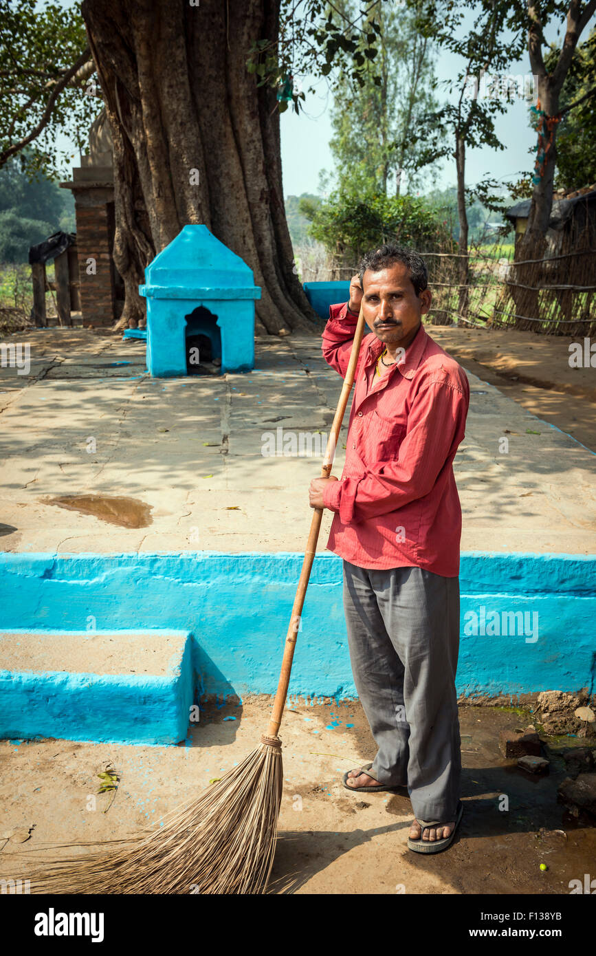 Un homme maintenant le sanctuaire hindou propre et rangé dans son petit village près de Chitrakoot, Madhya Pradesh, Inde Banque D'Images