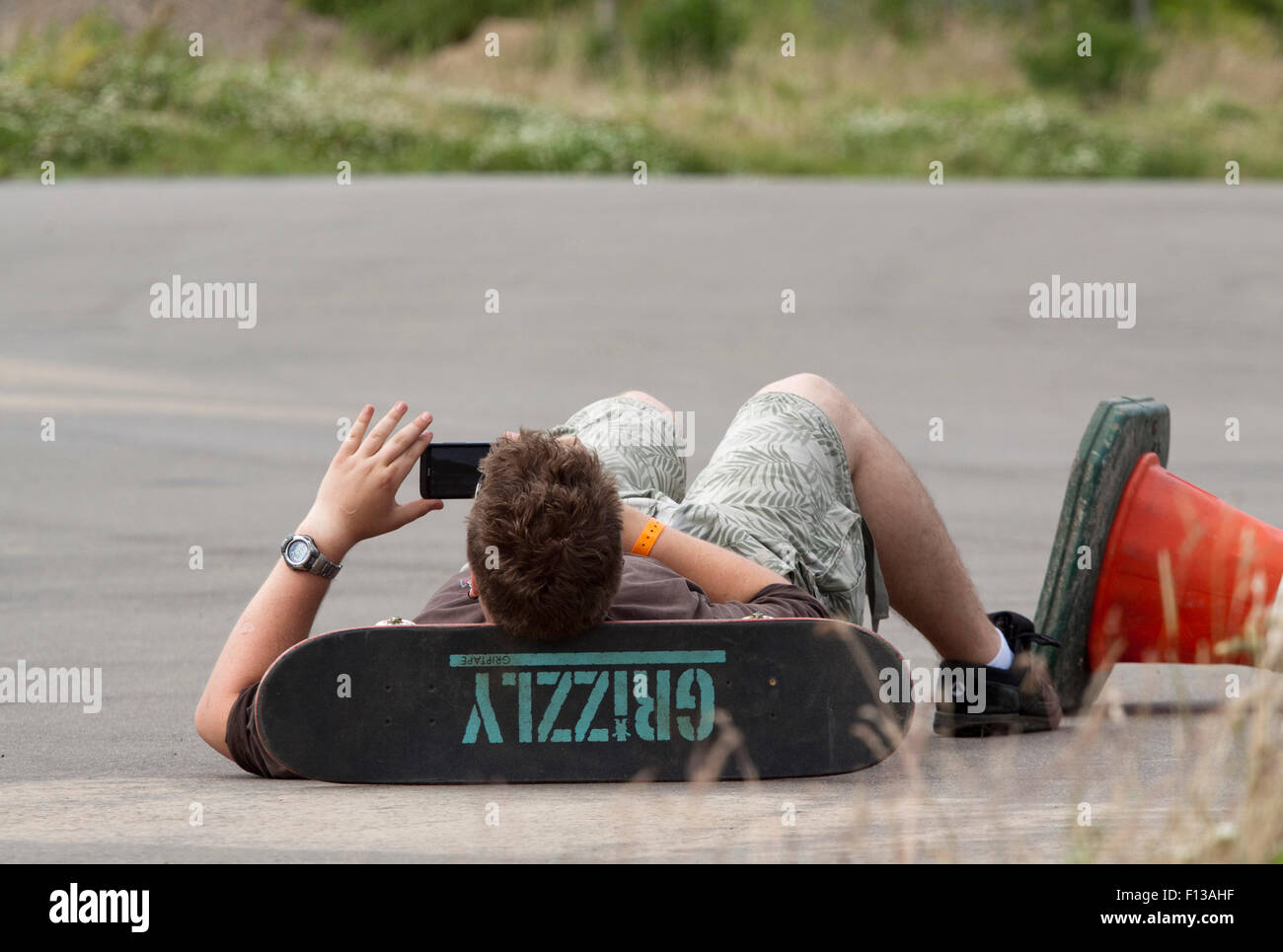 Jeune homme allongé sur le dos, appuyant sa tête sur son skateboard Banque D'Images