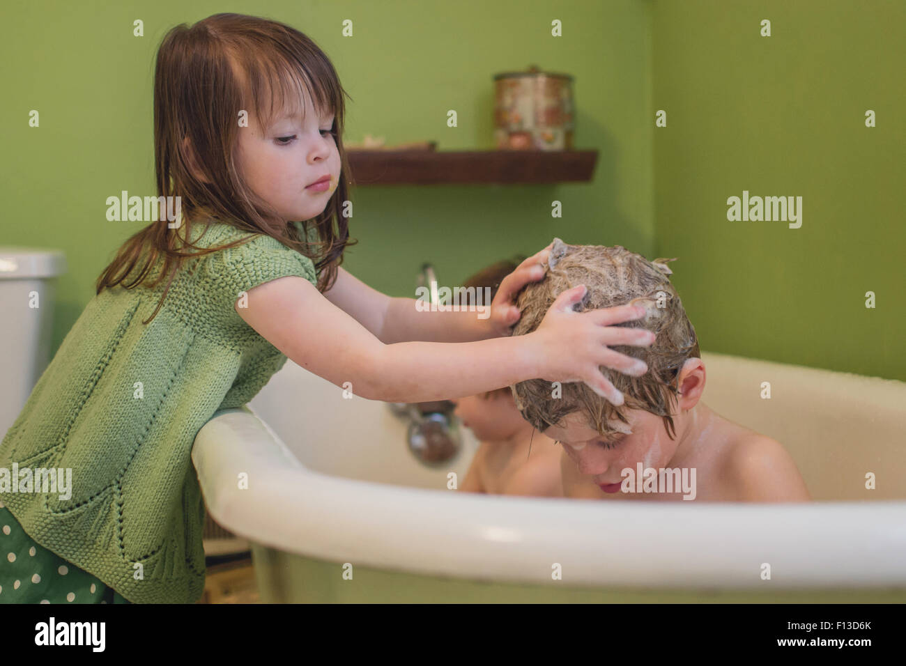 Fille se lavant les cheveux de son frère Banque D'Images