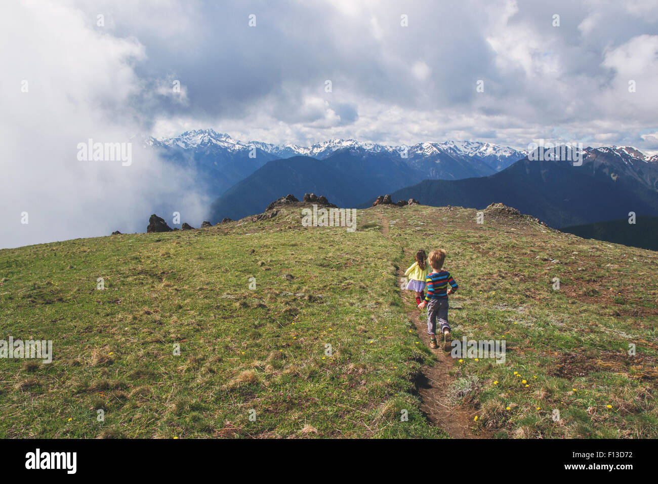 Garçon et fille courir le long d'un sentier de montagne Banque D'Images