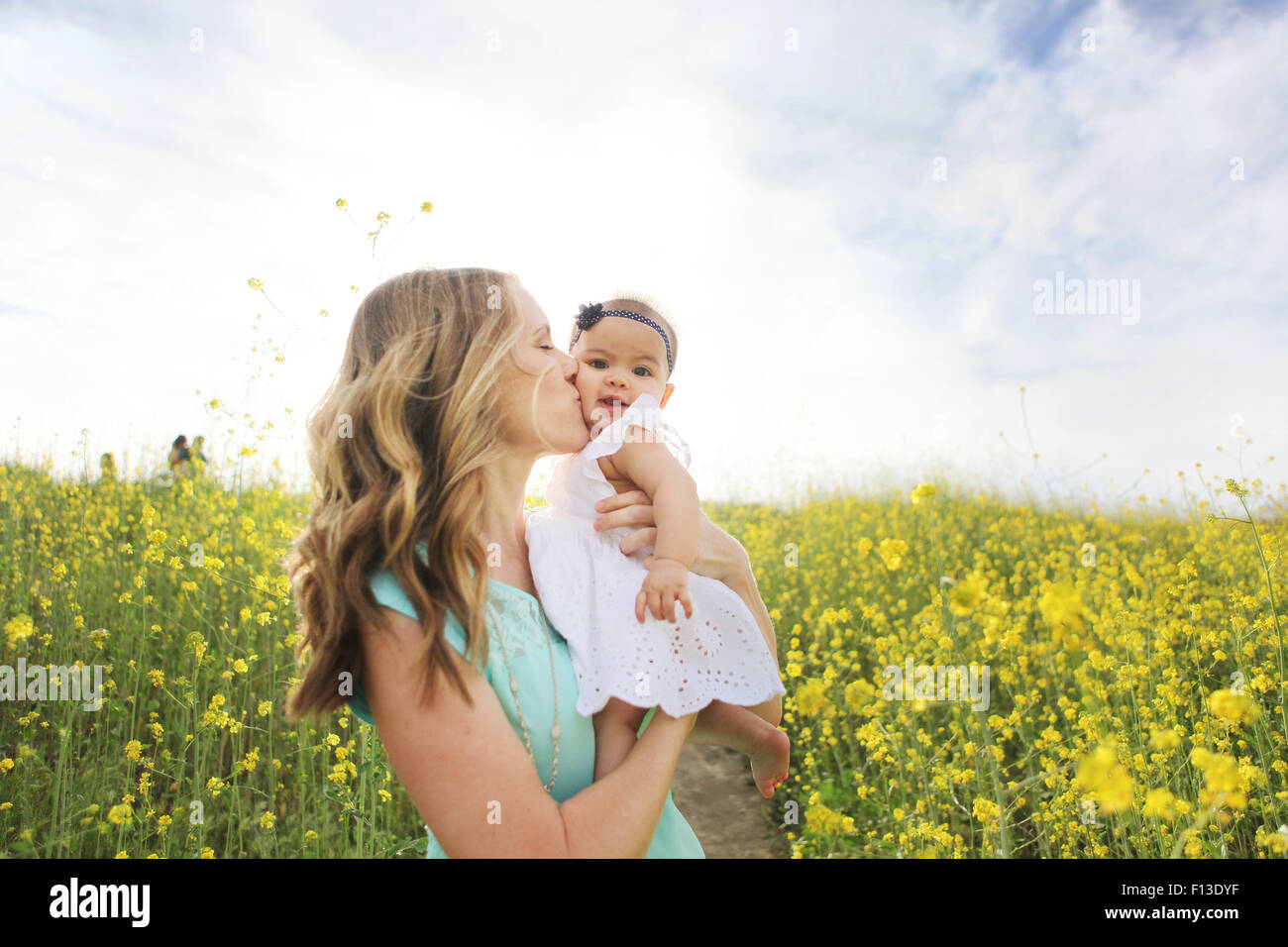 Mère embrassant bébé fille dans le champ de fleurs Banque D'Images