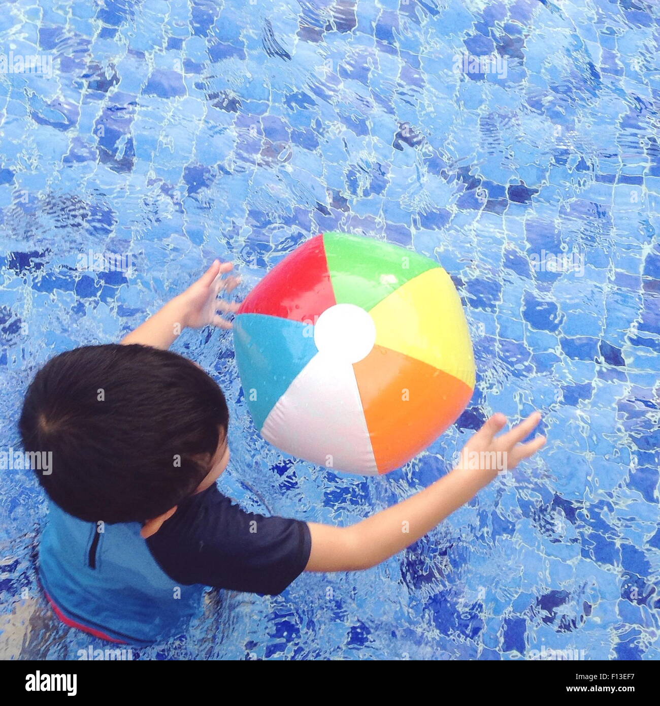 Vue aérienne d'un garçon jouant avec un ballon de plage dans la piscine Banque D'Images