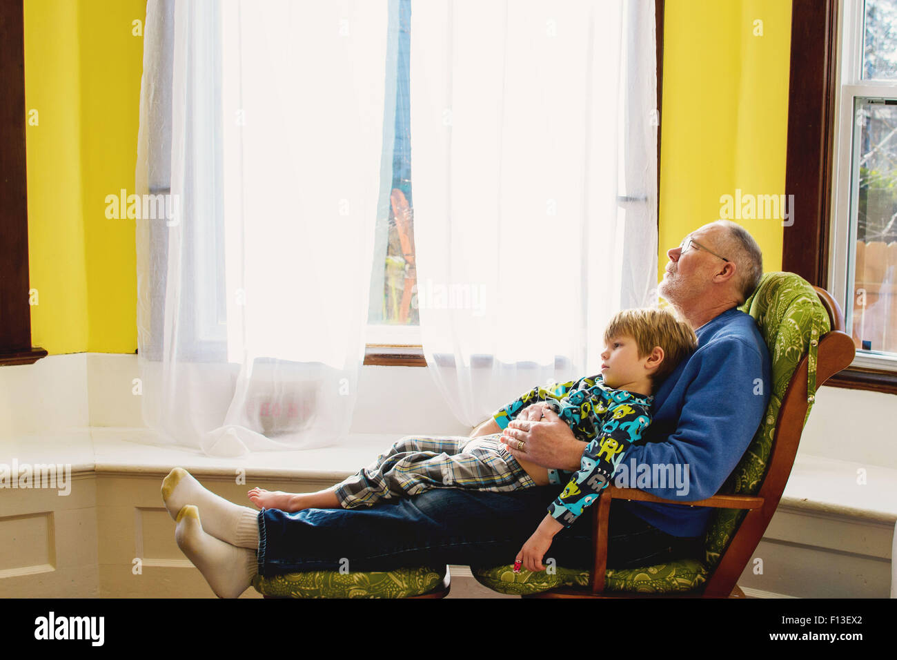 Garçon assis sur les genoux de son grand-père relaxing Banque D'Images