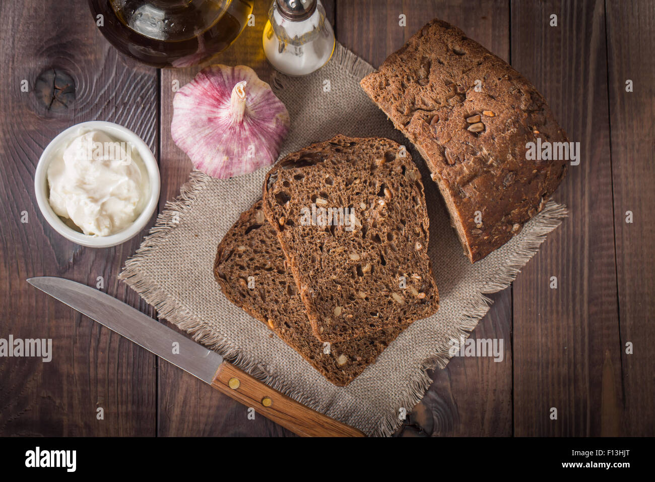 Tranches de pain de seigle, bouteille d'huile d'olive, l'ail, le sel et la sauce sur la table en bois Banque D'Images