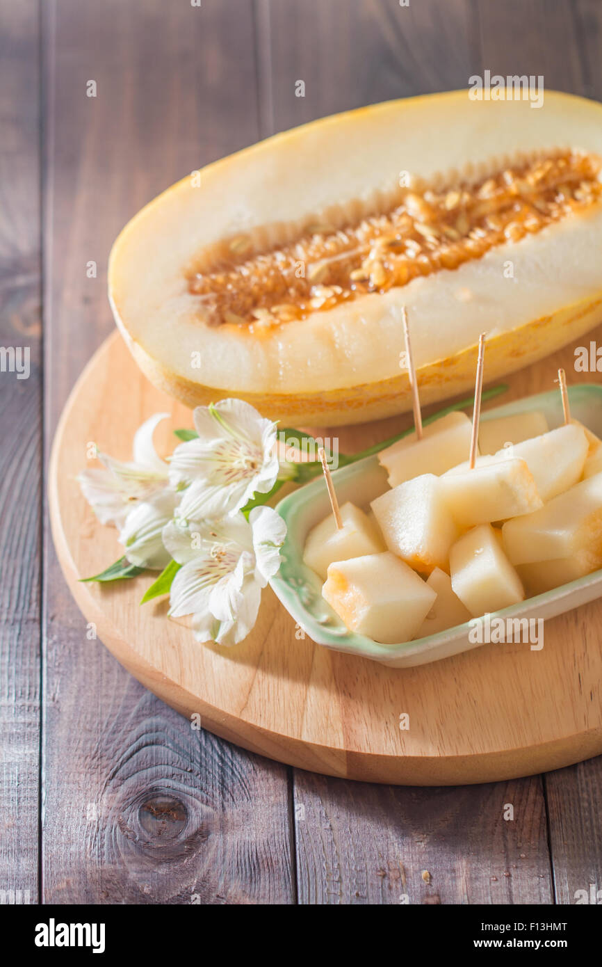 Melon frais avec des fleurs sur la coupe de bois Banque D'Images