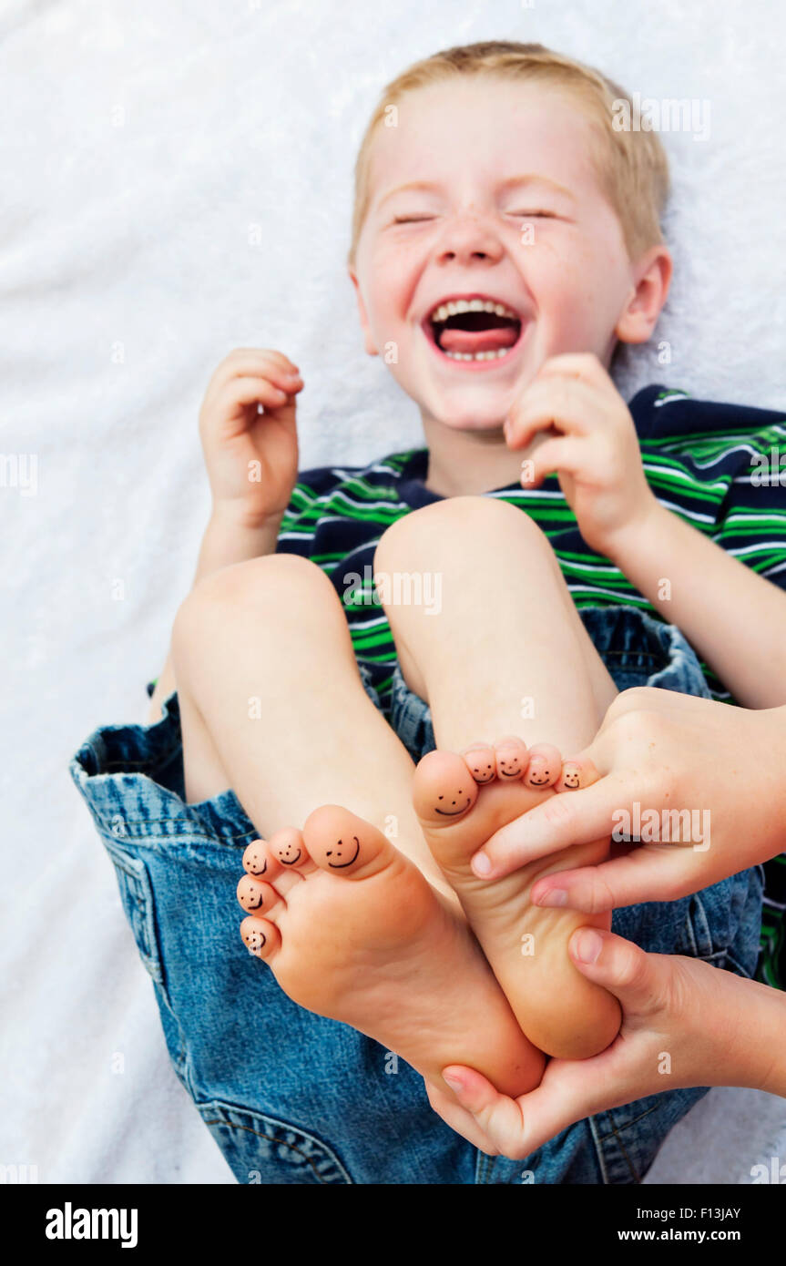 Enfant rire hystériquement lors de l'obtention de pieds chatouillés Banque D'Images