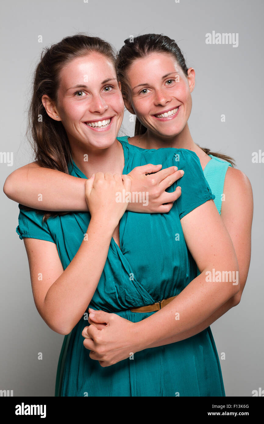 Deux Sœurs jumelles souriant Hugging Banque D'Images