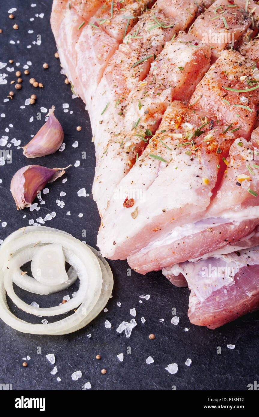La viande de porc fraîche avec des épices sur fond noir en noir Banque D'Images La viande de porc fraîche avec des épices sur fond noir en noir Banque D'Images