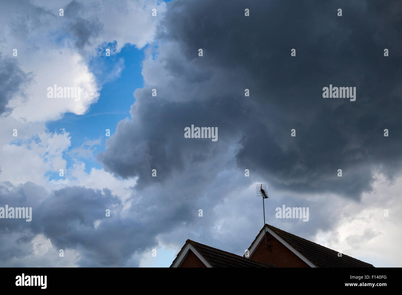Les nuages de tempête au-dessus d'un toit avec une antenne de télévision au Royaume-Uni Banque D'Images