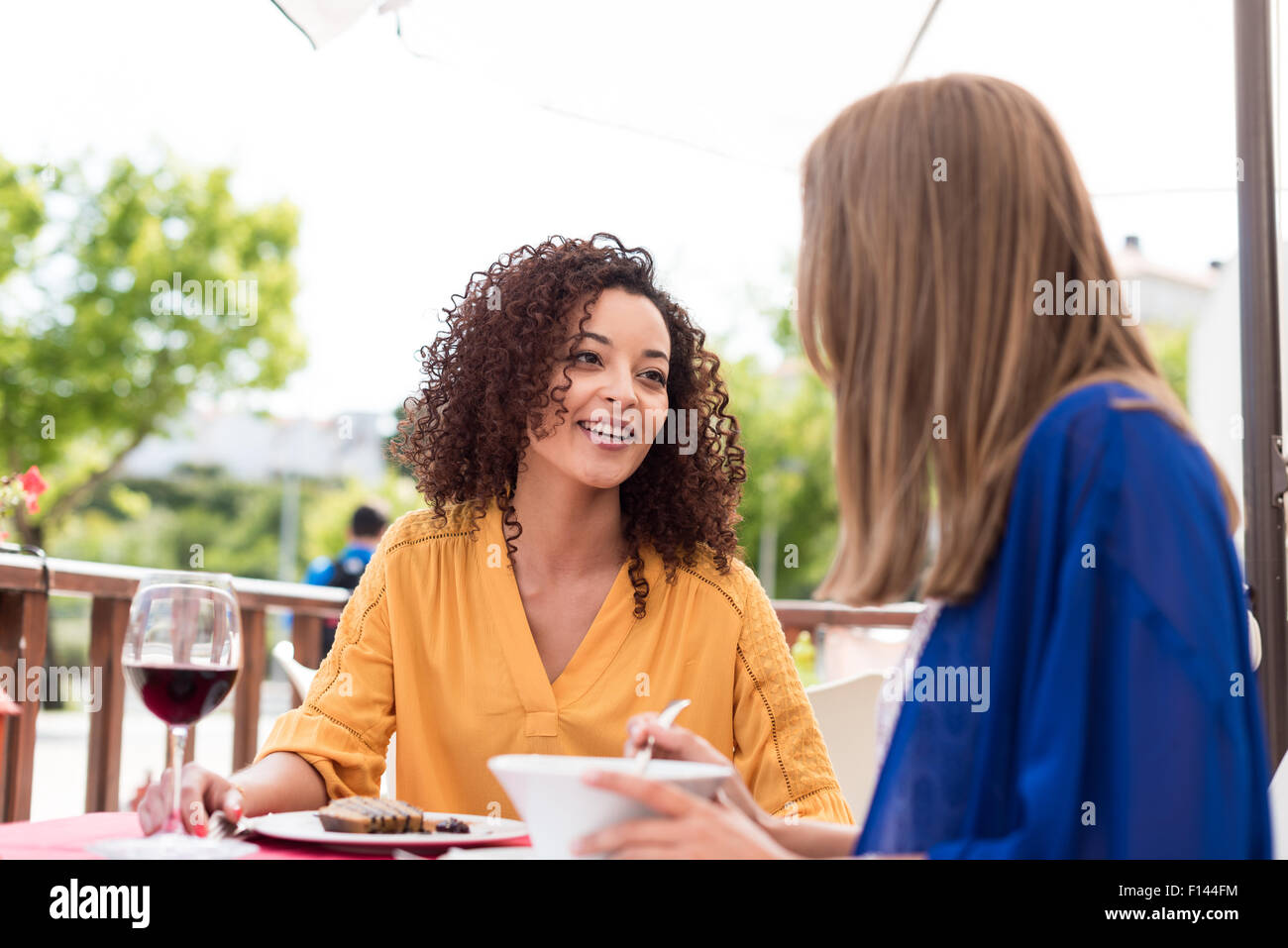 Personnes assises en train de boire un verre en terrasse en souriant et ...