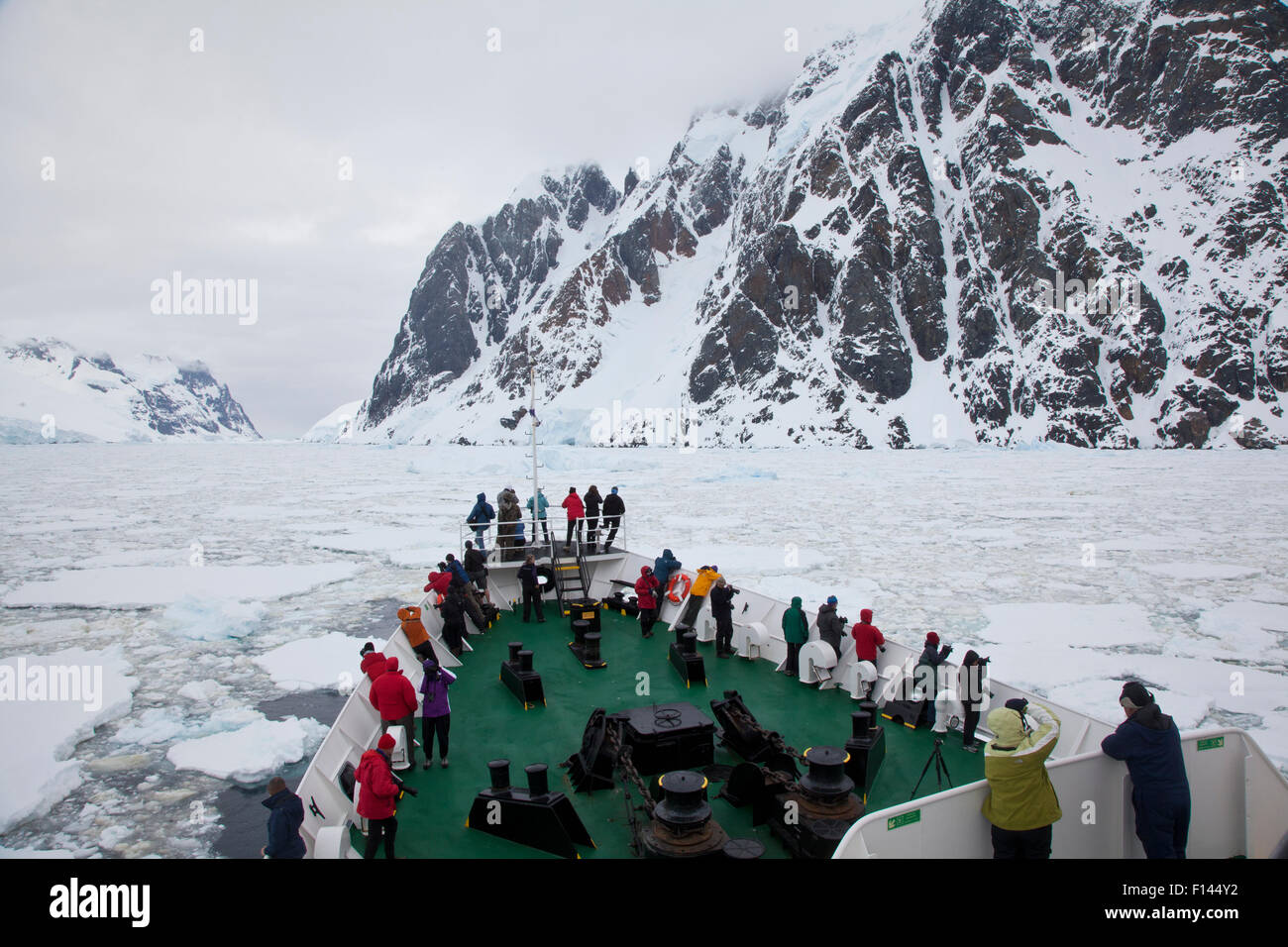 Les touristes qui tapissent le pont de bateau Ushuaia dans le Canal Lemaire colmatée par de la glace de mer, l'Antarctique. Banque D'Images