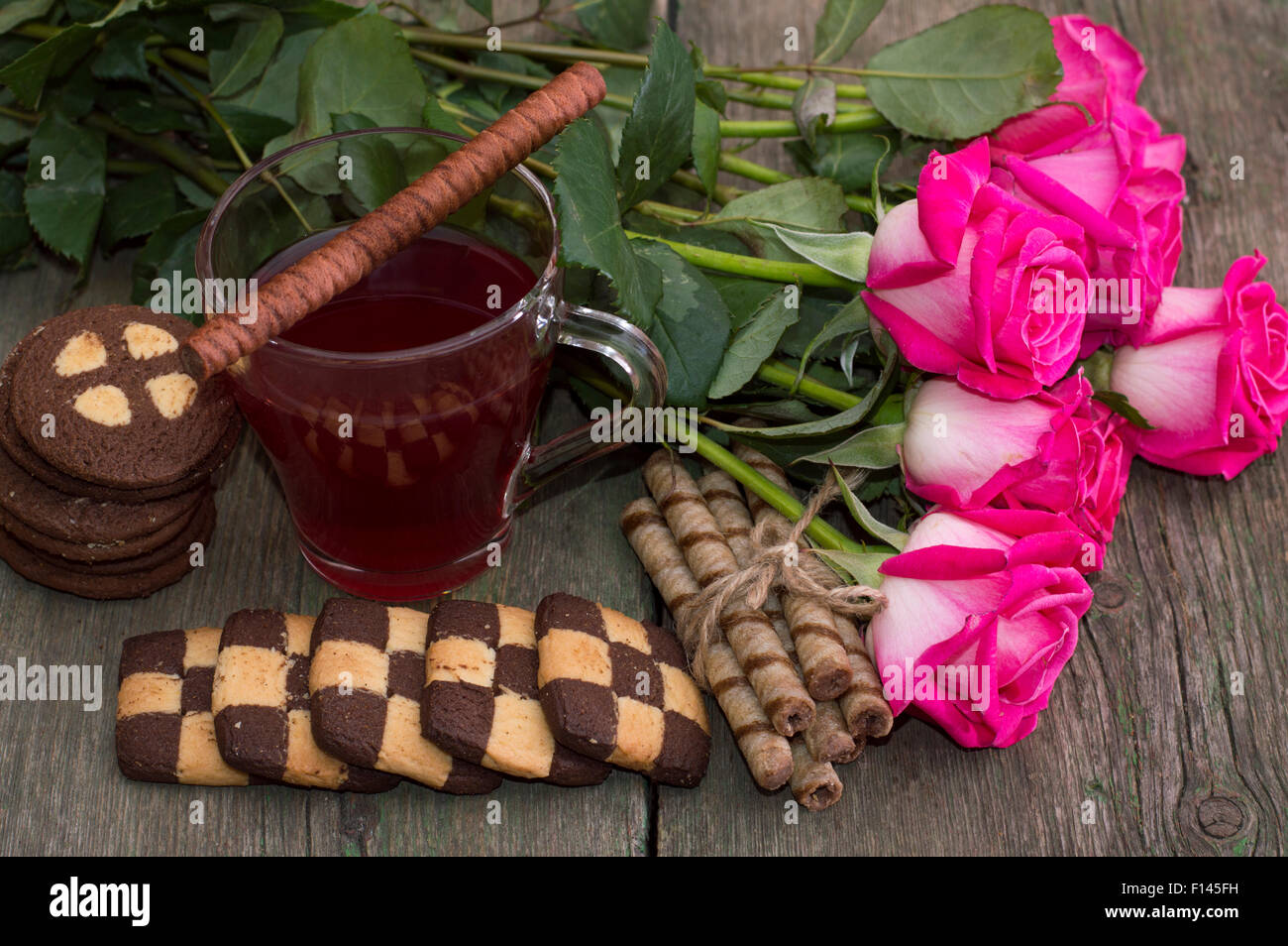 Belle nature morte de roses, des gâteaux et du thé sur une table en bois Banque D'Images
