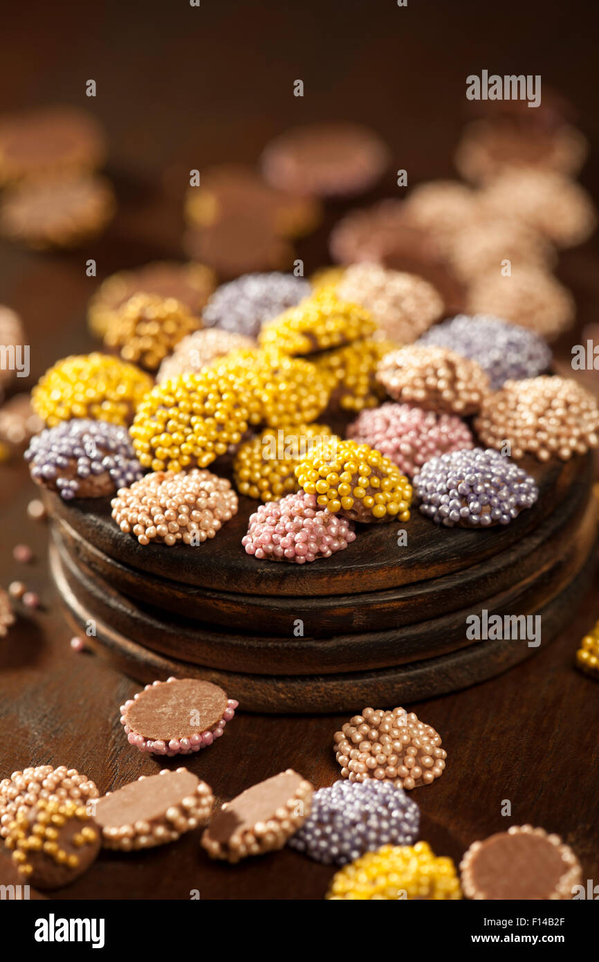 Dragées en chocolat colorés placés dans une surface en bois. Banque D'Images