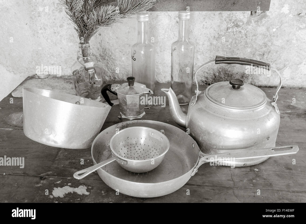Vieux objets sur une table de cuisine : casseroles, tamis, électrique, coffepot et trois bouteilles Banque D'Images