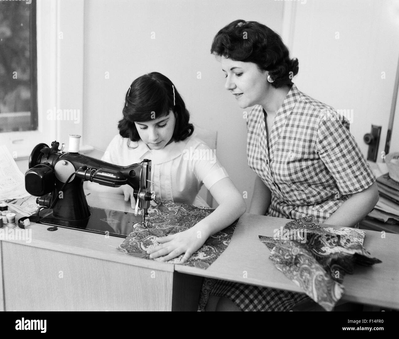 Années 1950 Années 1960 mère fille d'enseignement comment coudre à l'AIDE DE LA MACHINE À COUDRE Banque D'Images