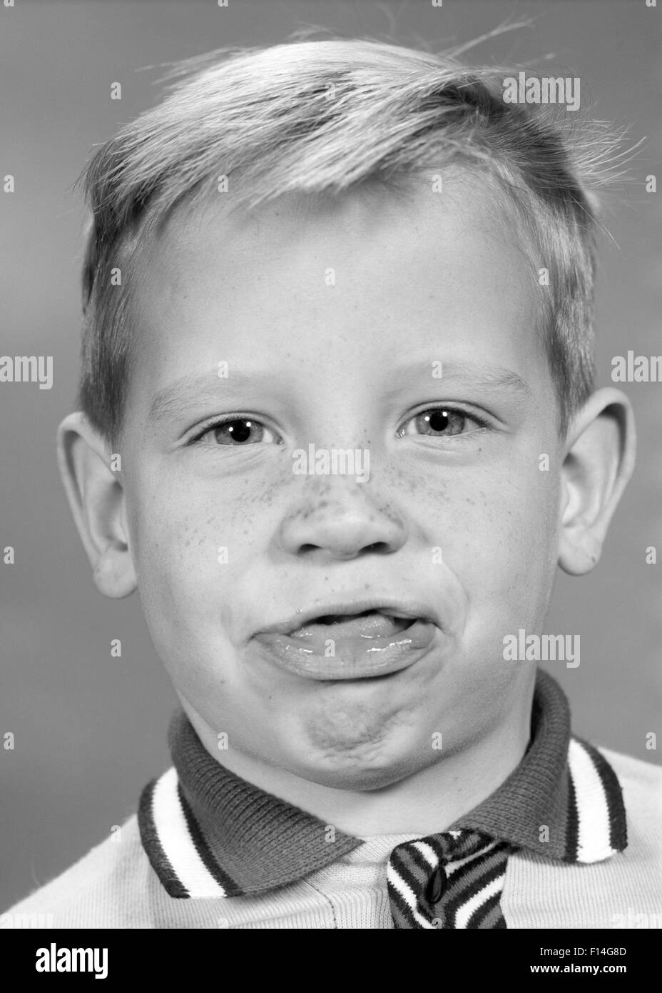 1960 LITTLE BOY STICKING OUT TONGUE LOOKING AT CAMERA DONNANT BRONX CHEER HUÉE CHAHUT railleries de framboise Banque D'Images