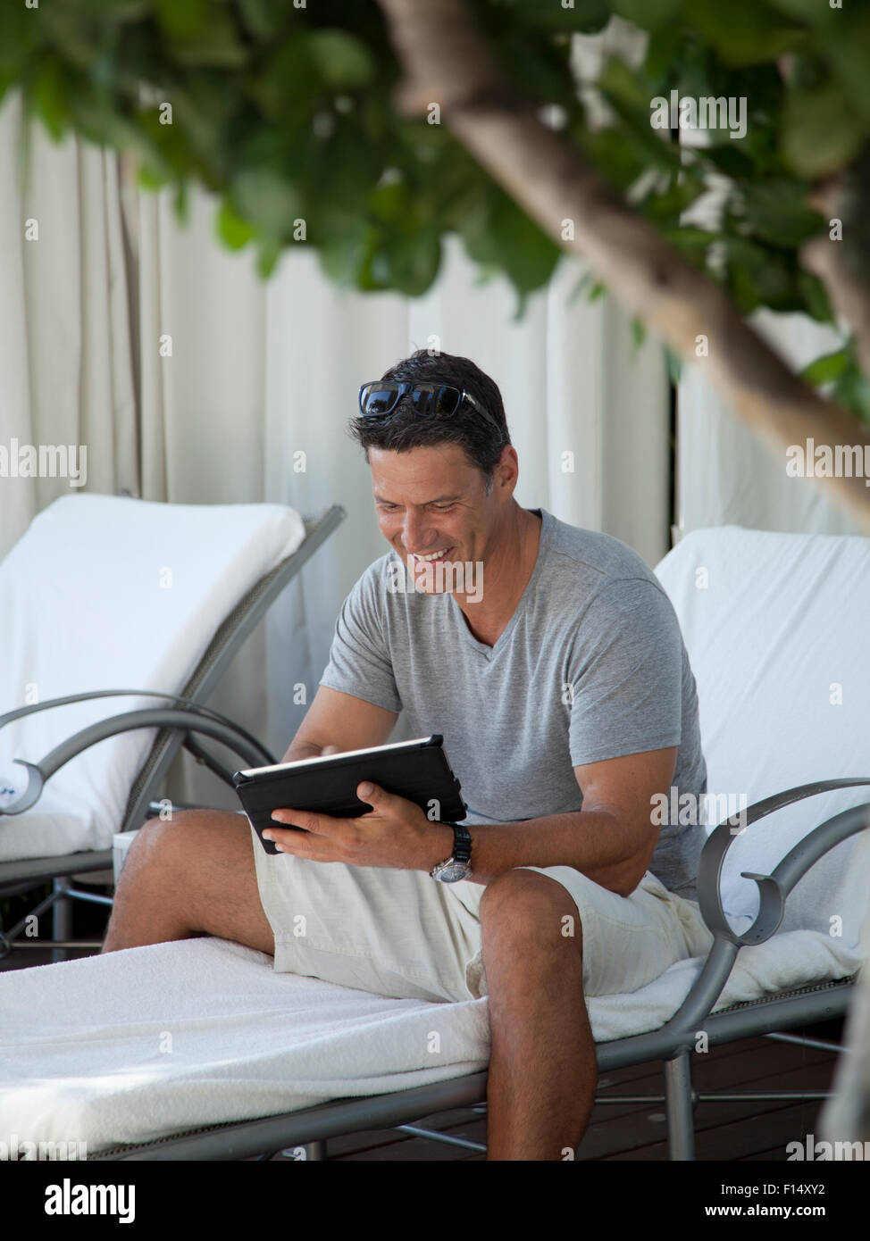 Homme assis sur chaise de salon using digital tablet Banque D'Images