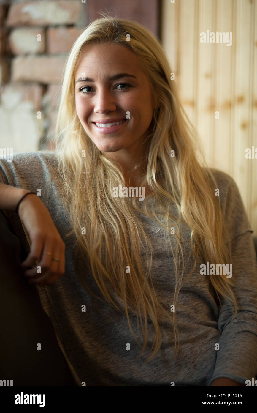 Femme heureuse avec de longs cheveux blonds sitting on sofa Banque D'Images
