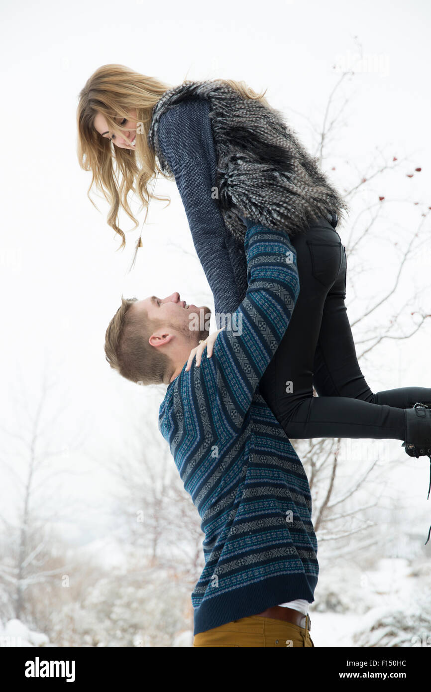 Low angle view of happy man looking up et petite amie de levage dans la neige Banque D'Images