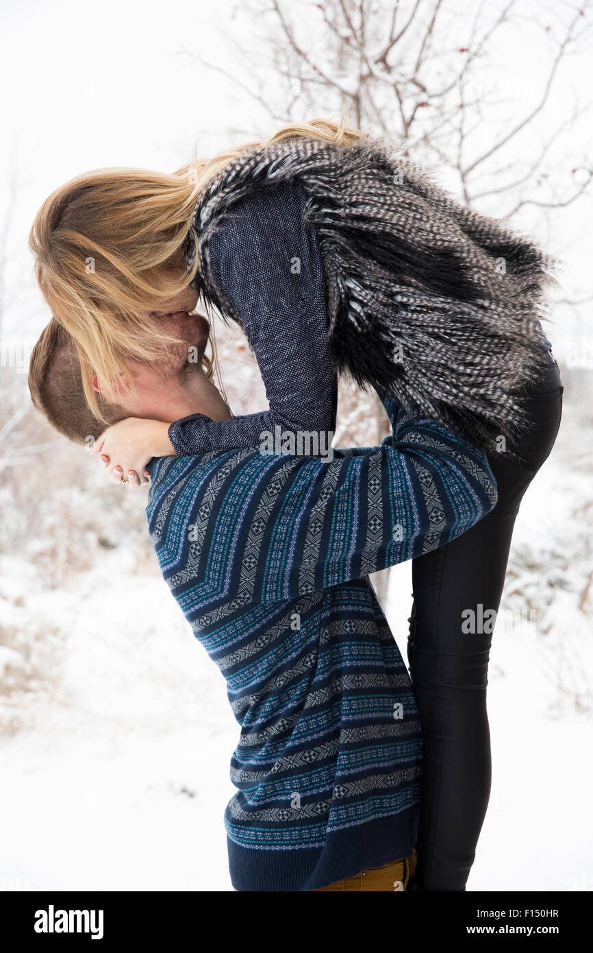 Vue latérale d'homme heureux et de levage des baisers petite amie dans la neige Banque D'Images