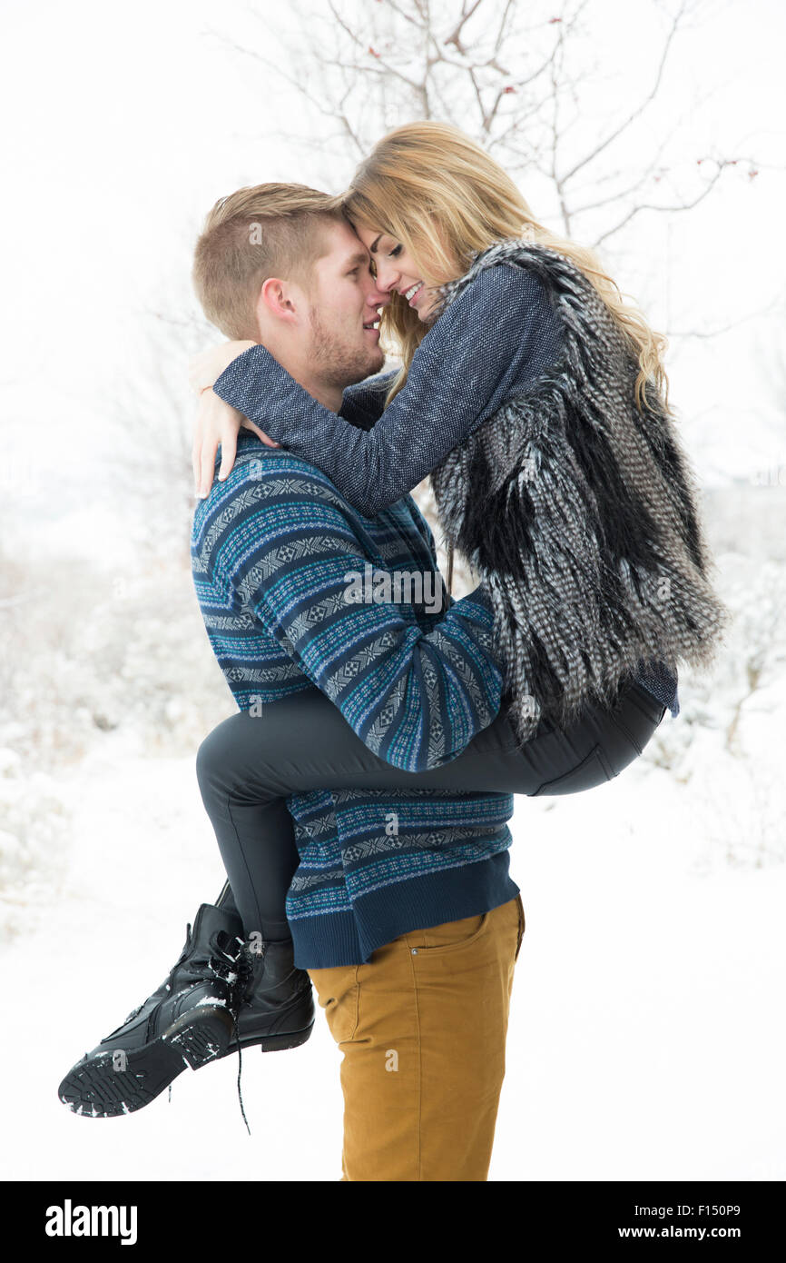 Vue latérale d'happy man hugging and holding girlfriend in snow Banque D'Images