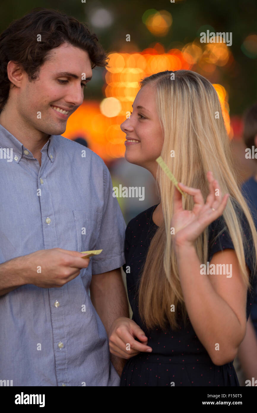 Le partage ludique heureux couple snack au parc d'amusement juste Banque D'Images