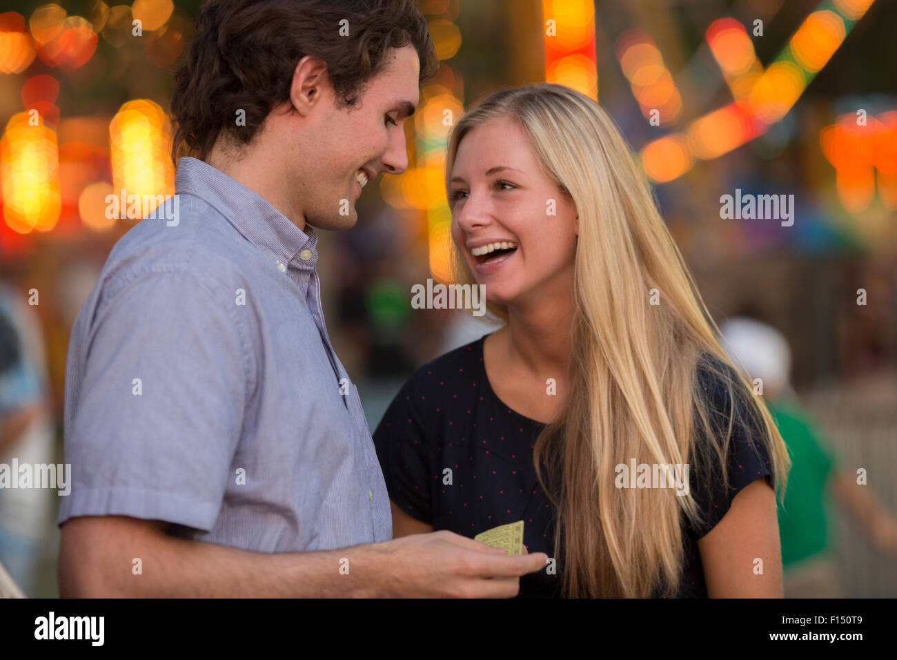 Happy laughing couple talking at amusement park fun fair Banque D'Images