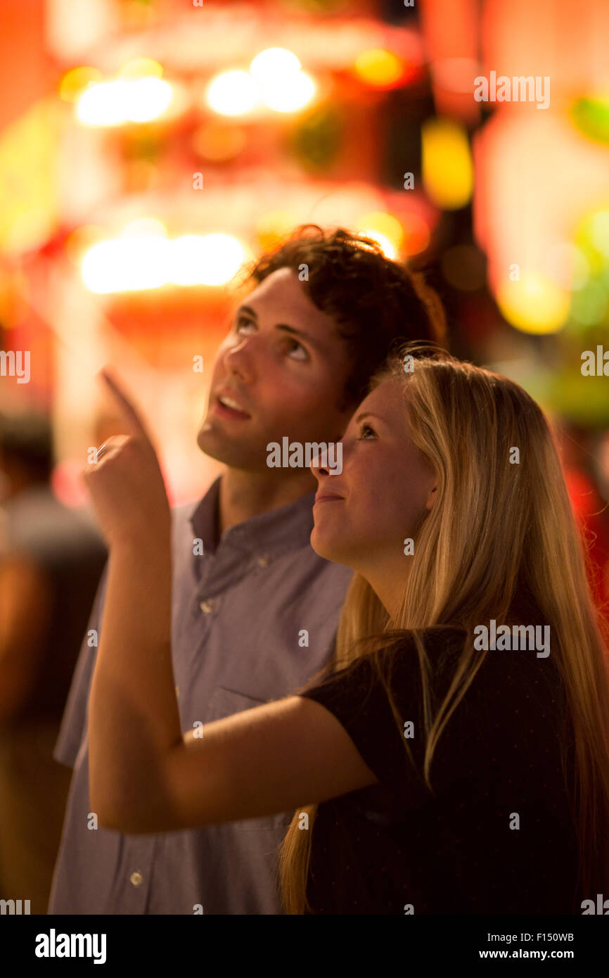 Profil de l'heureux couple looking up and gesturing with blurred face au parc d'amusement juste Banque D'Images