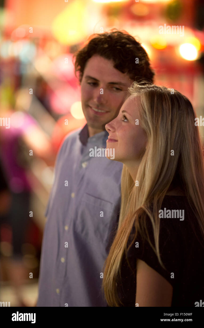 Profil de l'heureux couple looking up at amusement park fun fair Banque D'Images