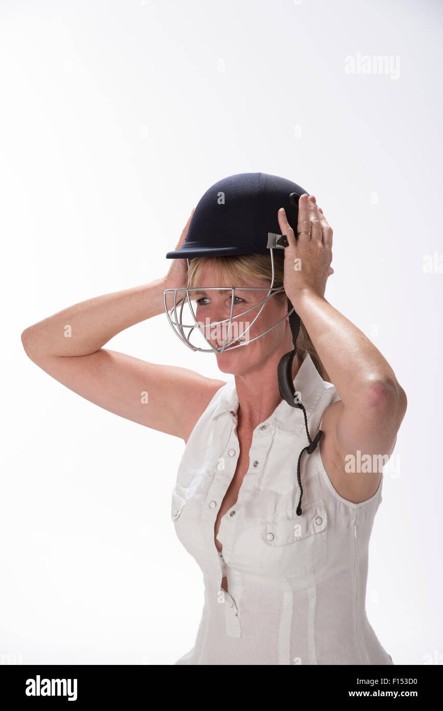 Portrait d'une femme cricketer ajustant son casque de sécurité Banque D'Images
