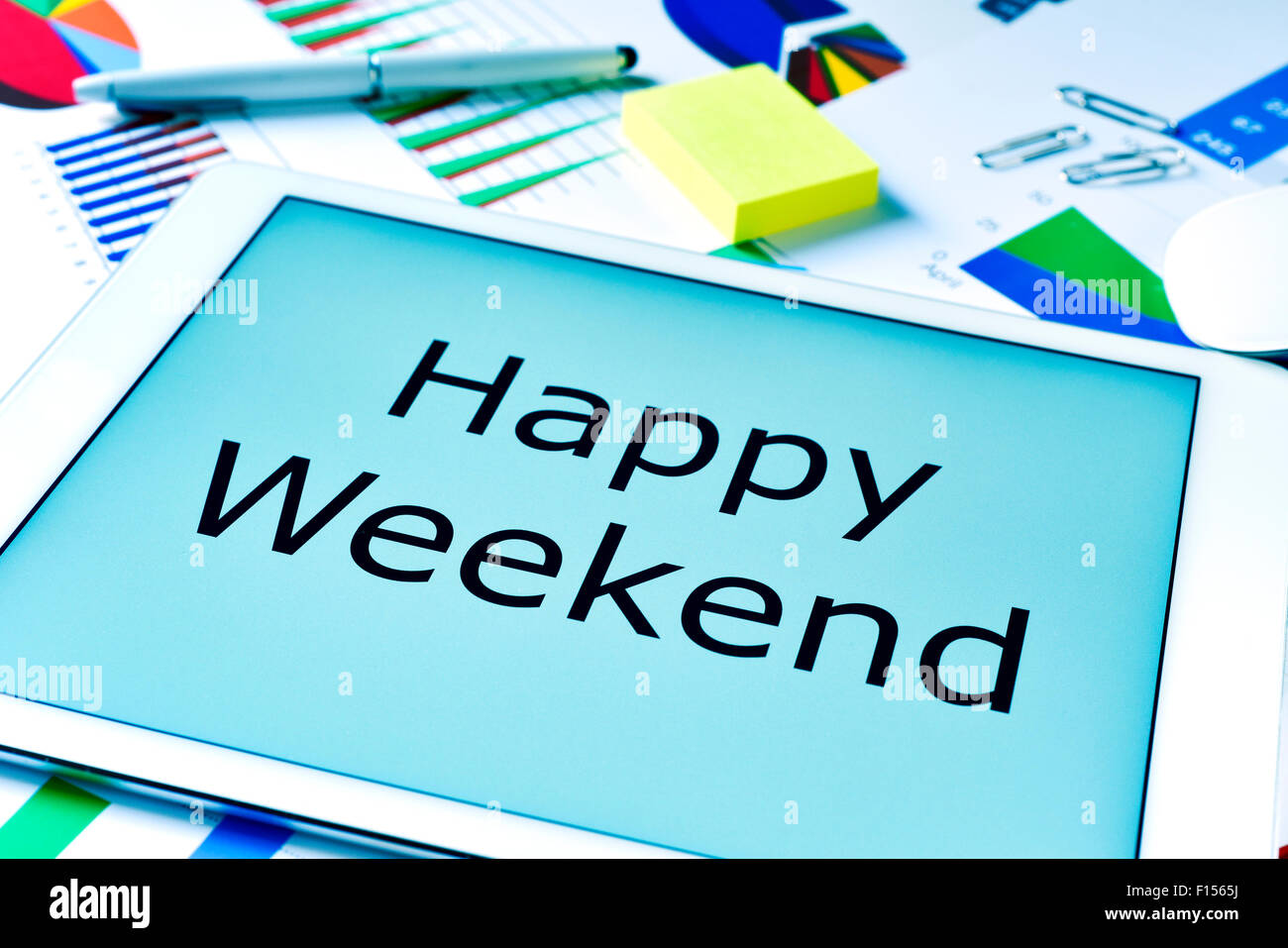 Le texte happy weekend dans l'écran d'une tablette, placé sur une table pleine de cartes marines Banque D'Images