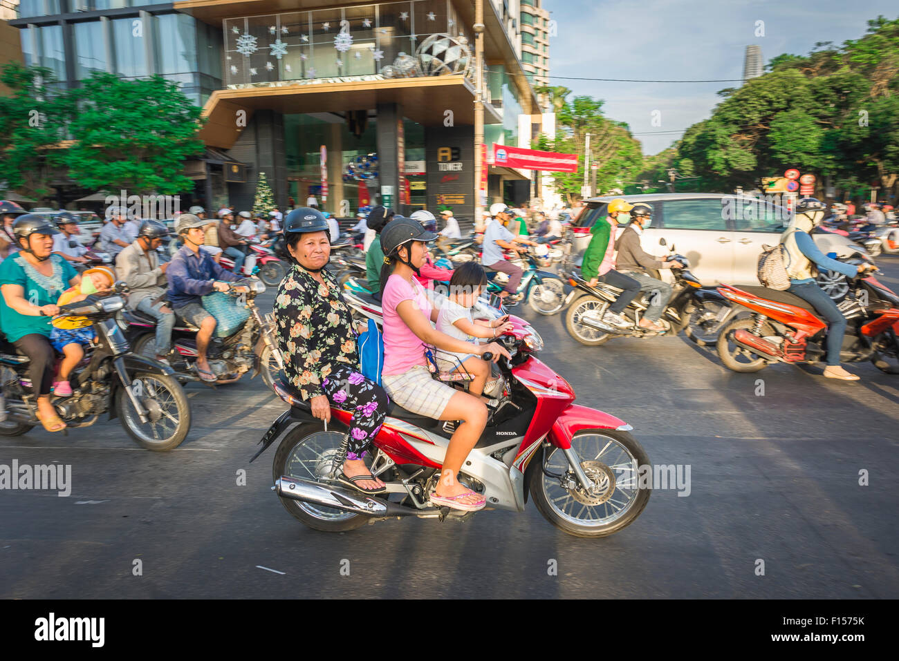 Moto famille Vietnam, trois générations partagent un tour à l'heure de pointe à Pham Ngu Lao Dong dans le centre de Ho Chi Minh Ville, HANOI, SAIGON, Vietnam. Banque D'Images
