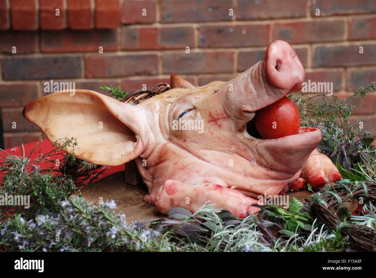 Une tête de porc avec une pomme rouge planté dans sa bouche à un banquet de style médiéval. Banque D'Images