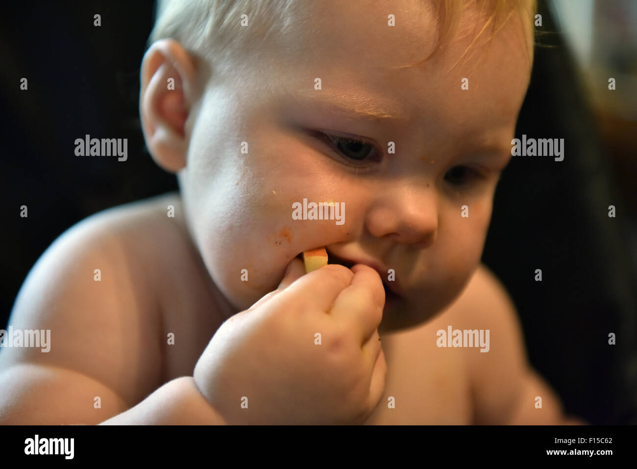 Un Portrait D Un Bebe De 11 Mois Dentition Assis Sur Une Chaise Haute De Manger Une Tranche De Pomme Photo Stock Alamy